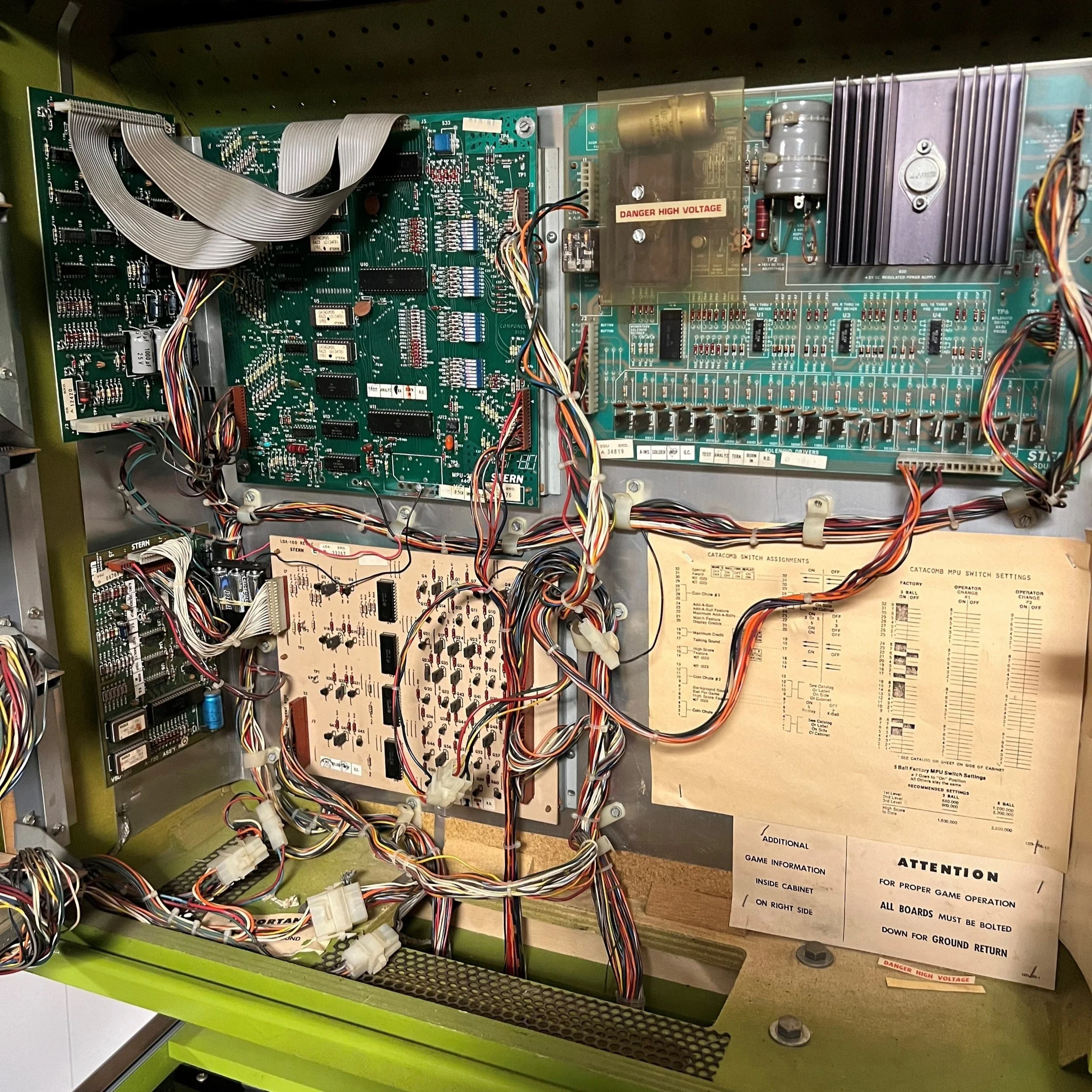 Interior view of a vintage pinball machine with circuit boards and wiring.