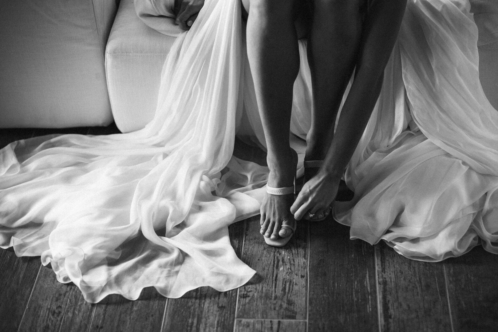 bride putting on her shoes wearing a beautiful dress in black and white