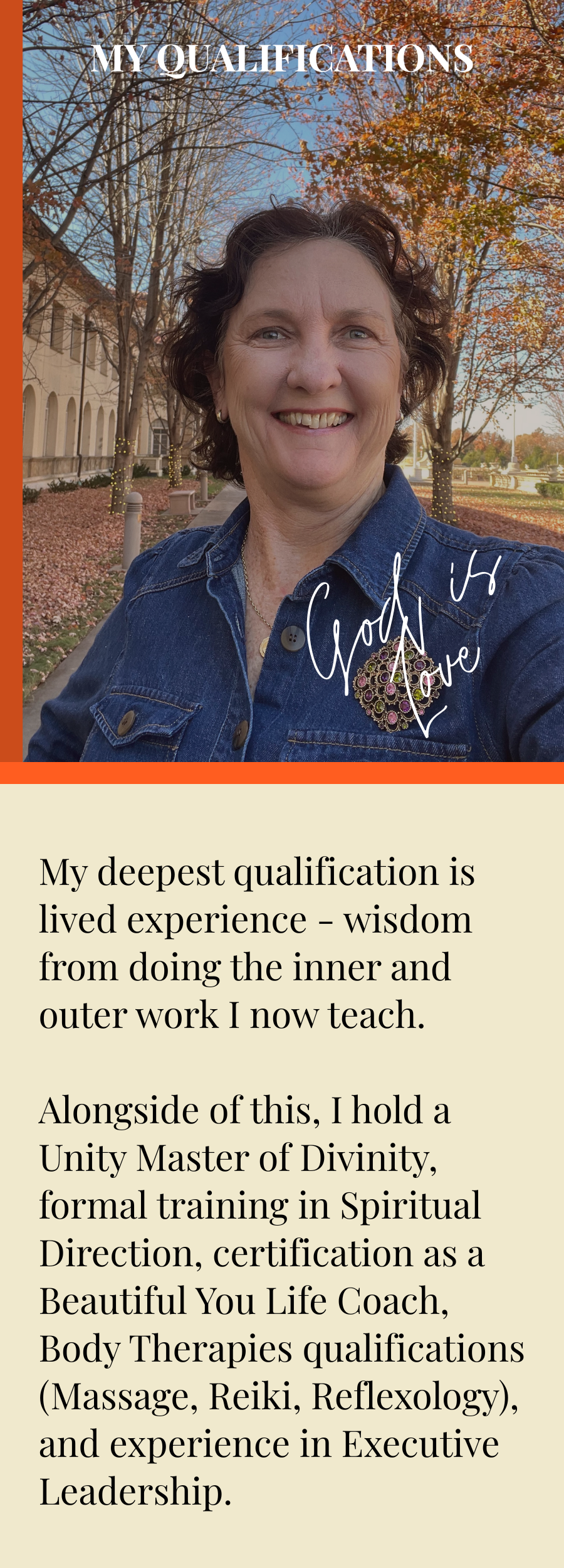 A smiling woman taking a selfie outdoors during autumn, with trees showing fall foliage and a building in the background, wearing a denim jacket with a decorative brooch.