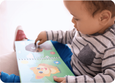 A young child reading a colorful children's book with animal illustrations.