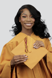 Young woman in a yellow graduation gown holding a diploma and a yellow folder, smiling