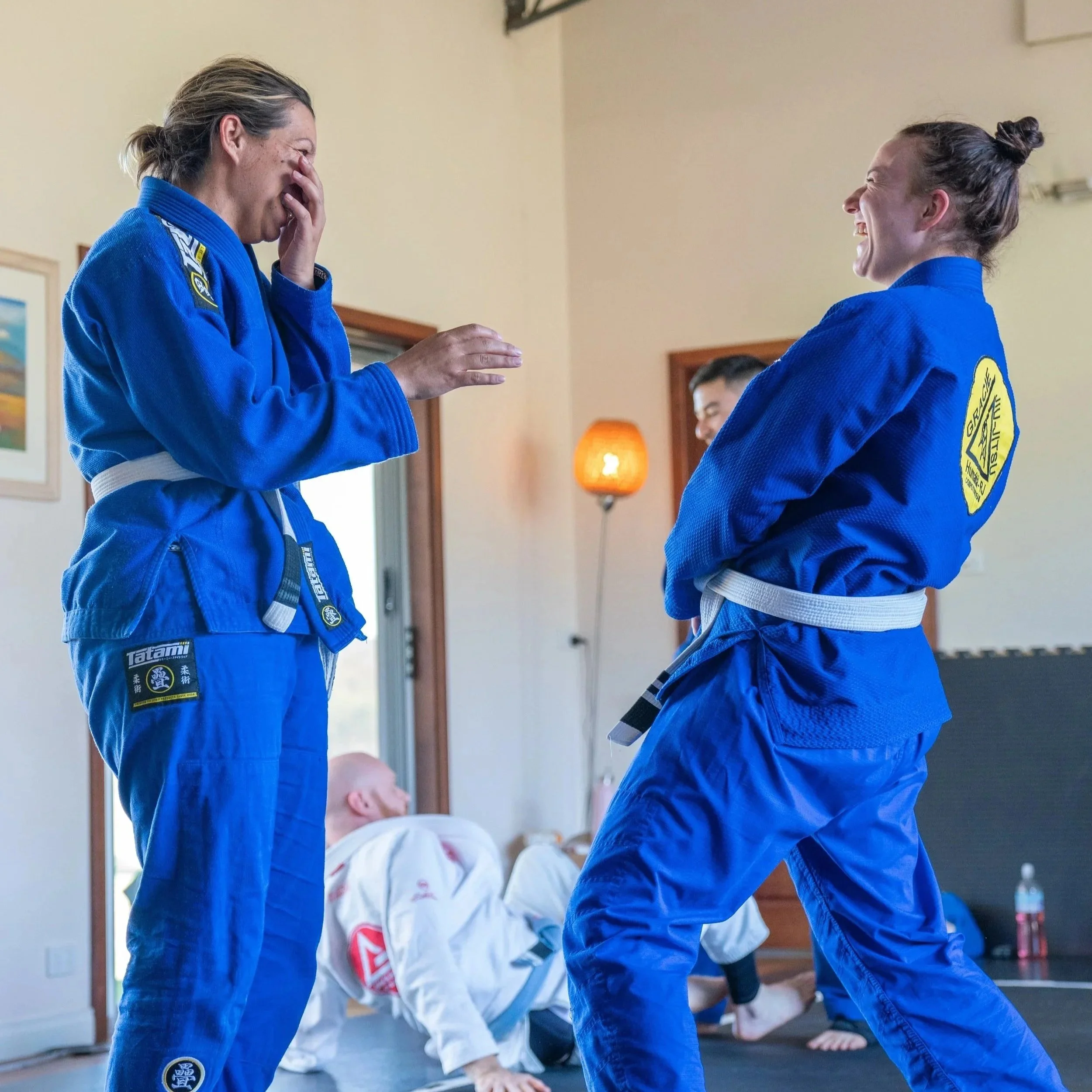 Female BJJ retreat participants in blue gis laughing and having fun