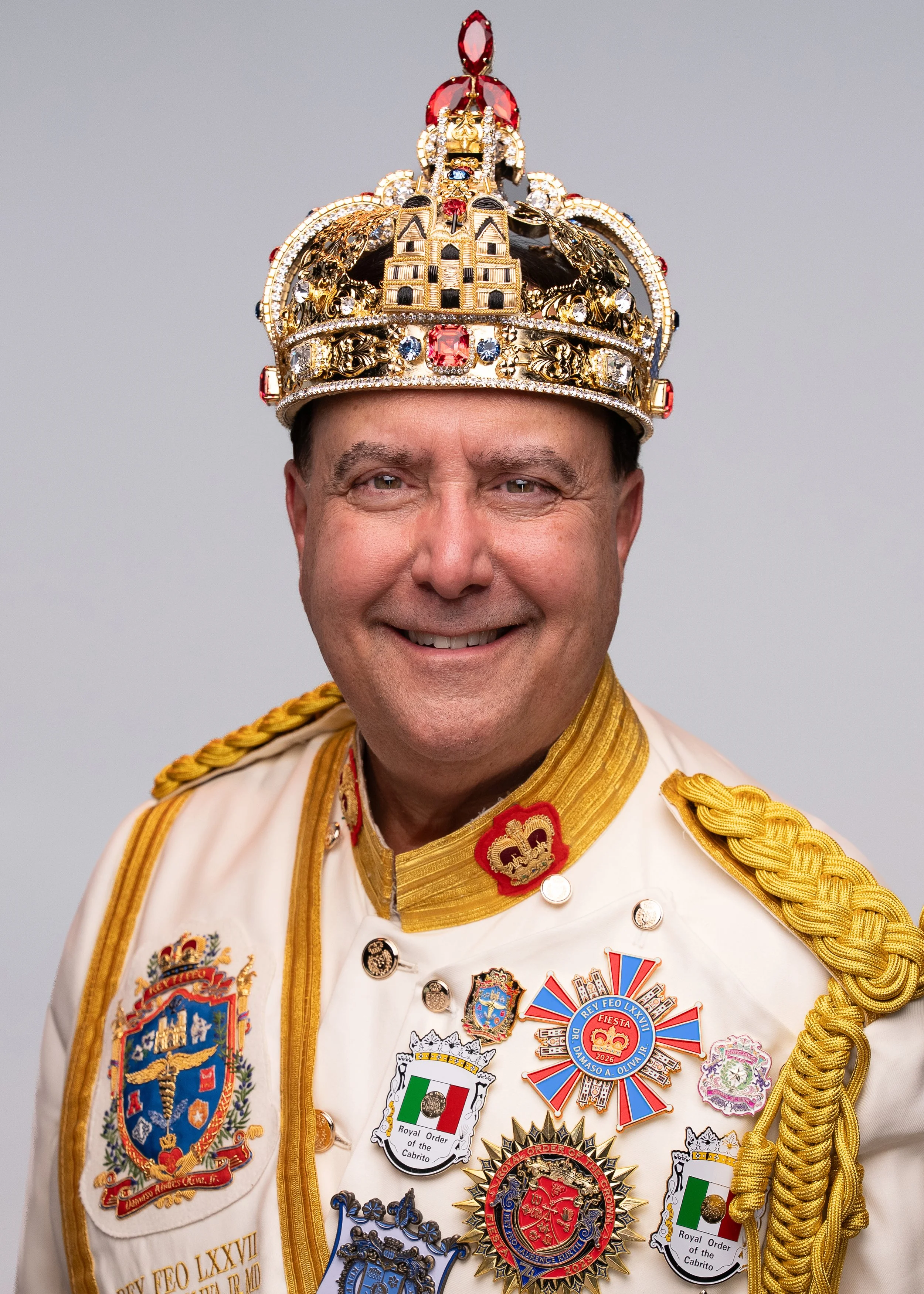 Headshot of a smiling middle-aged man with dark hair in a red button-up shirt against a light gray background.