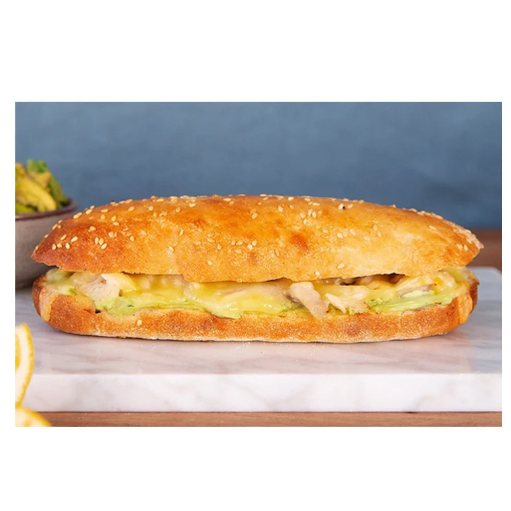 A sandwich with bread, melted cheese, and lettuce on a white marble surface.