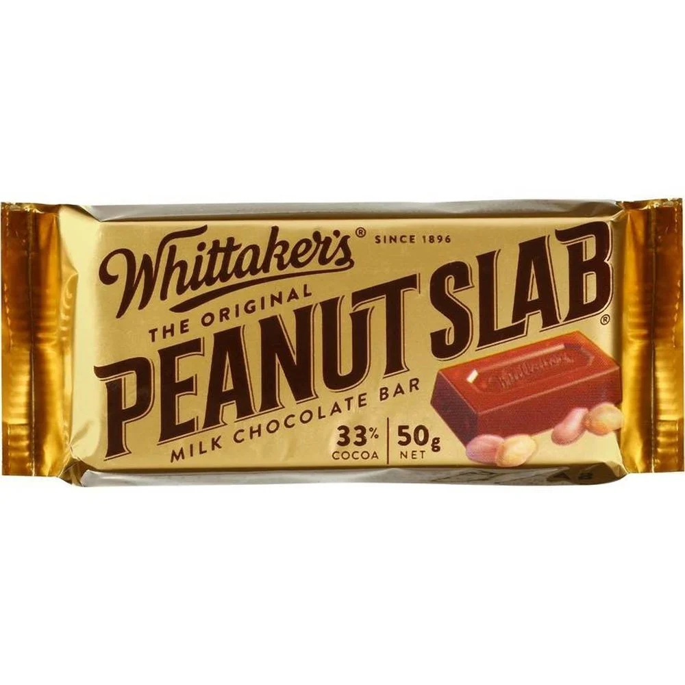 A Whittaker's Peanut Slab milk chocolate bar with gold packaging, a red chocolate piece, and peanuts, indicating the flavor.