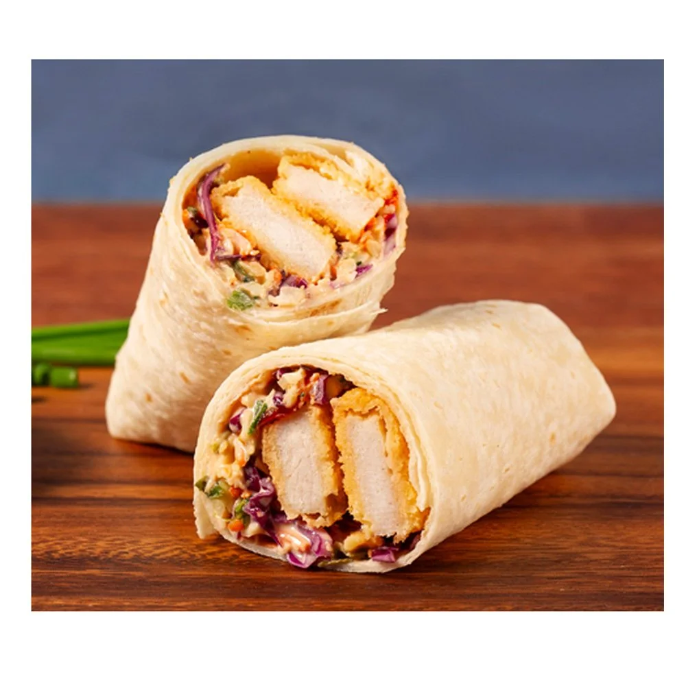 Two chicken Caesar wraps on a wooden surface, one cut in half showing shredded chicken, lettuce, and Caesar dressing inside