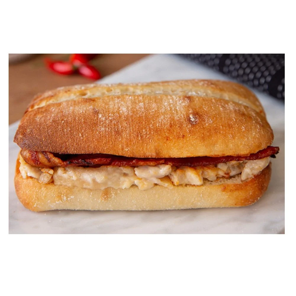 A sandwich with chicken salad and bacon on a bread roll.