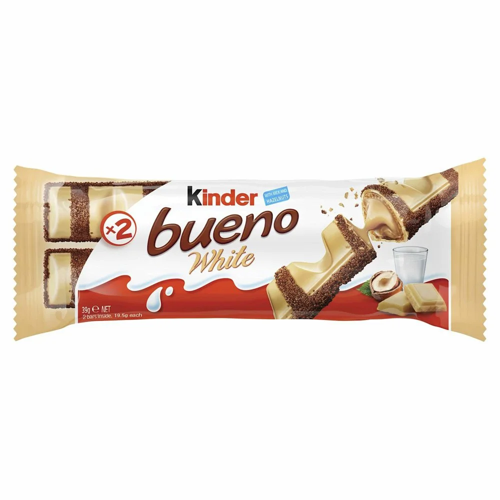 Package of Kinder Bueno White chocolate bars, showing two bars with white chocolate coating and a hazelnut filling, along with a glass of water and hazelnuts in the background.