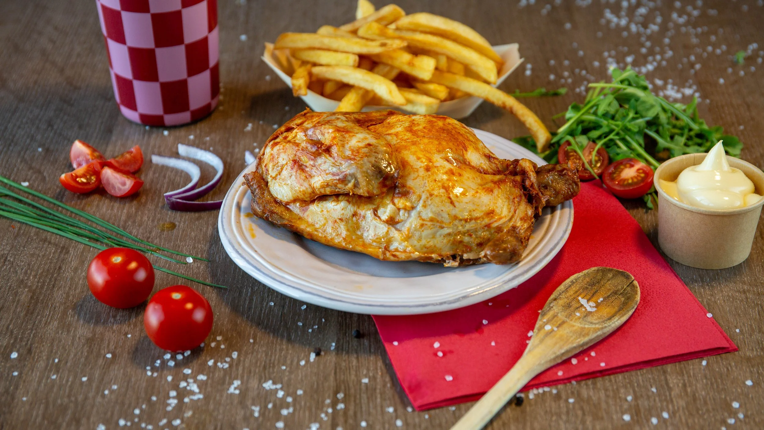 Kip met frieten, salade, en tomaat op een tafel