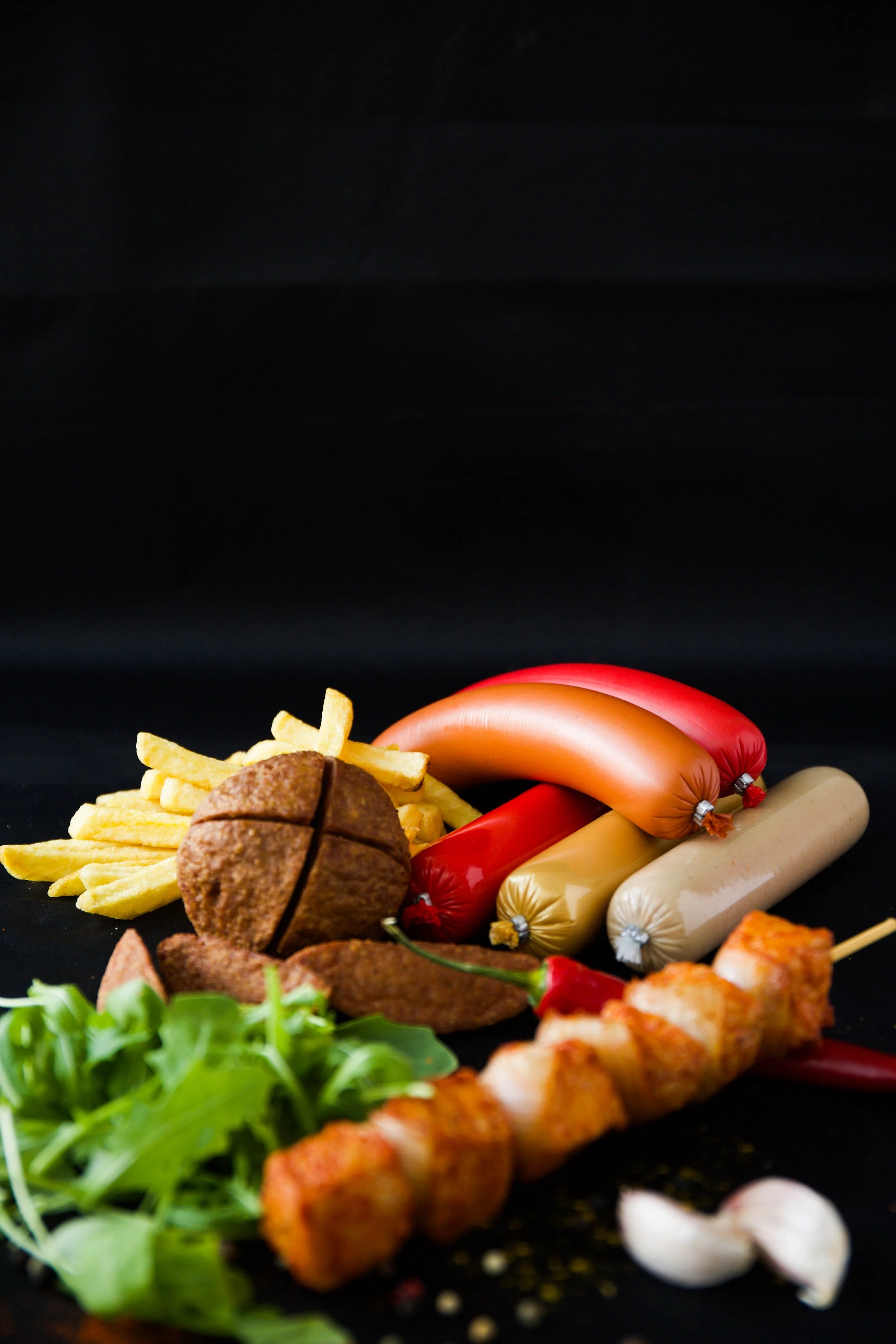 Assortiment van drop, frieten, gekookt ei, salade en gefrituurde snack op zwarte achtergrond.