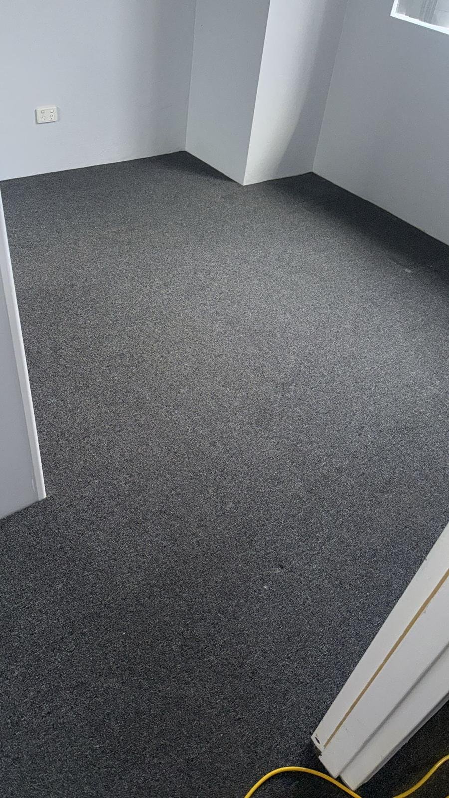 Empty room with gray carpet, white walls, a window, and a power outlet.