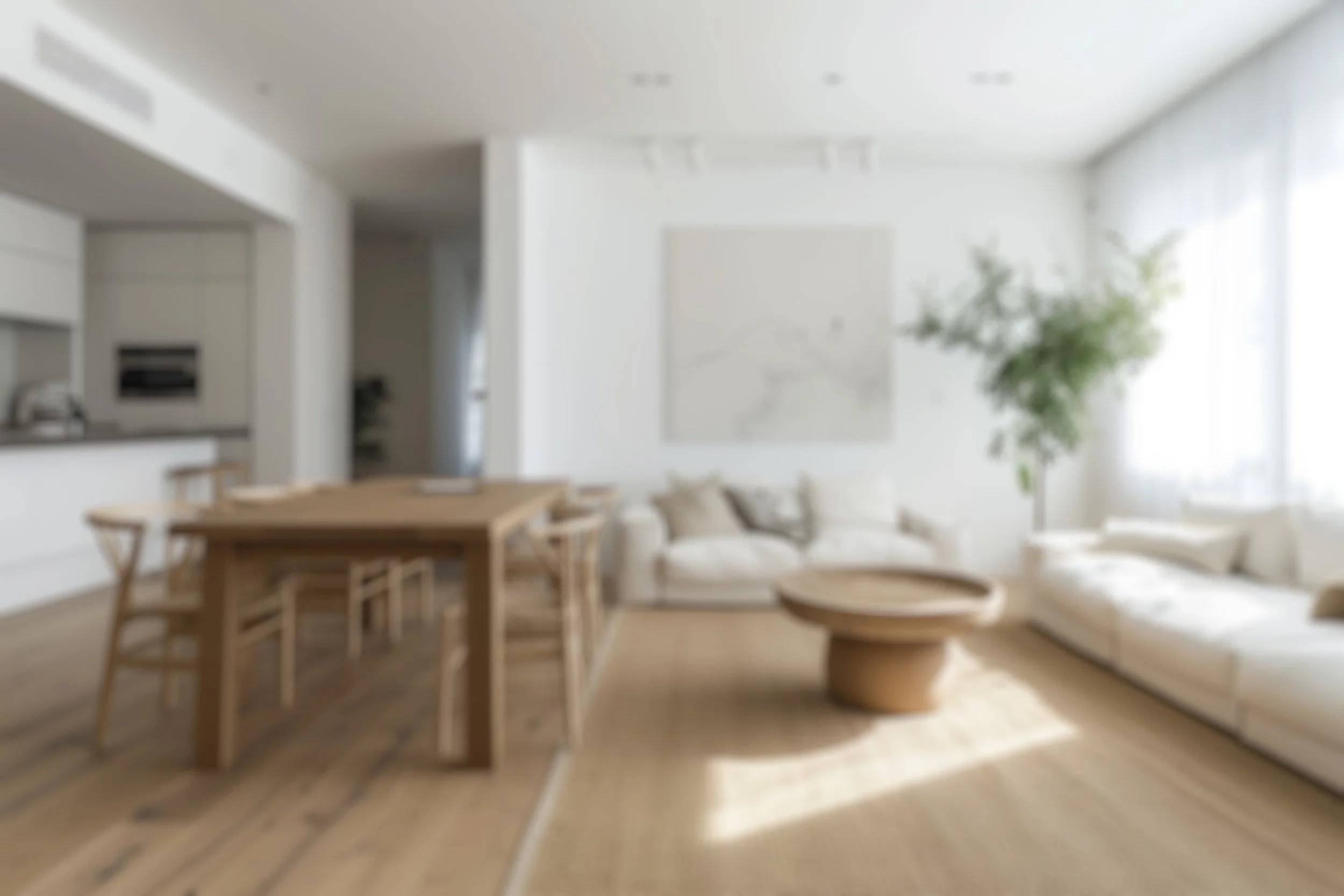 A cozy living room with white sofas, a round wooden coffee table, a large potted plant, and a dining table with chairs, all illuminated by natural light from large windows.
