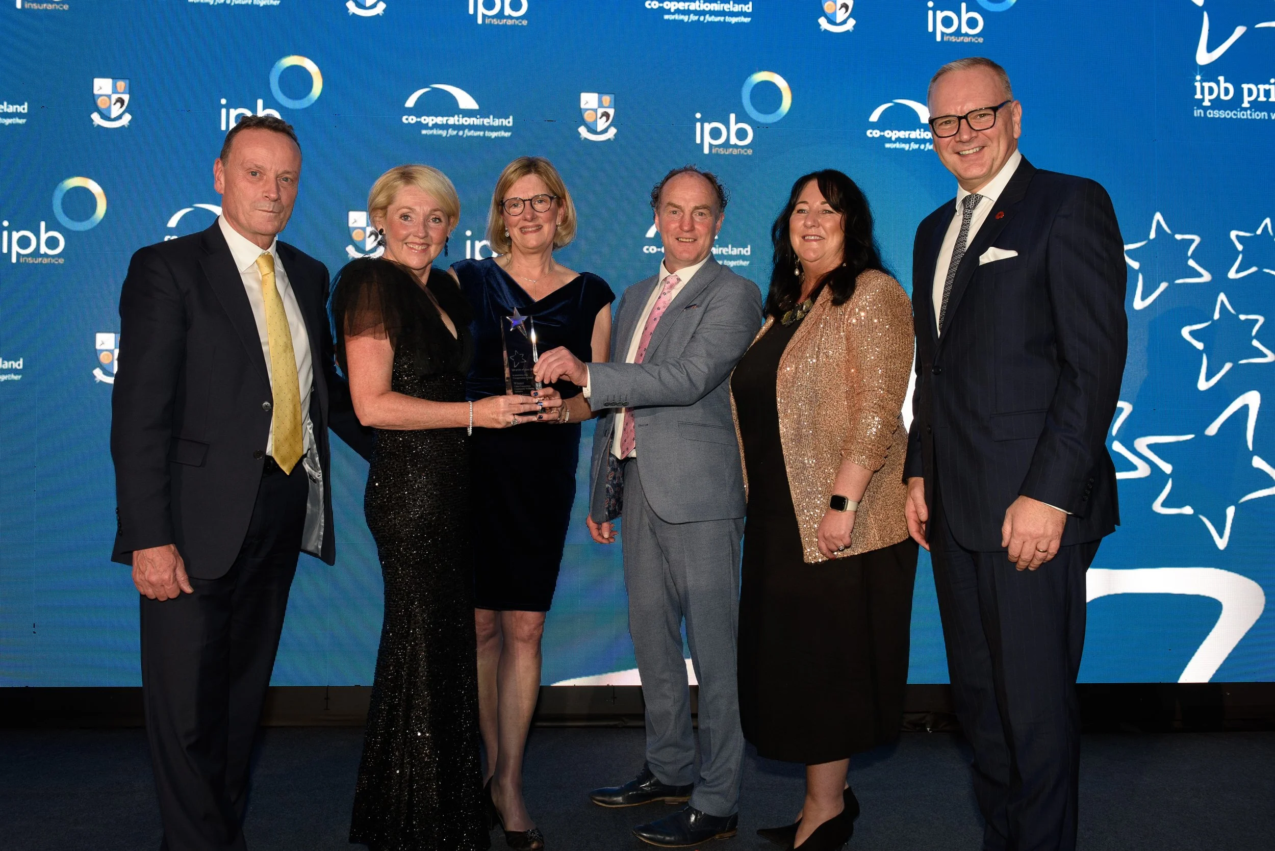 Group of people receiving an award on stage with branded blue background.