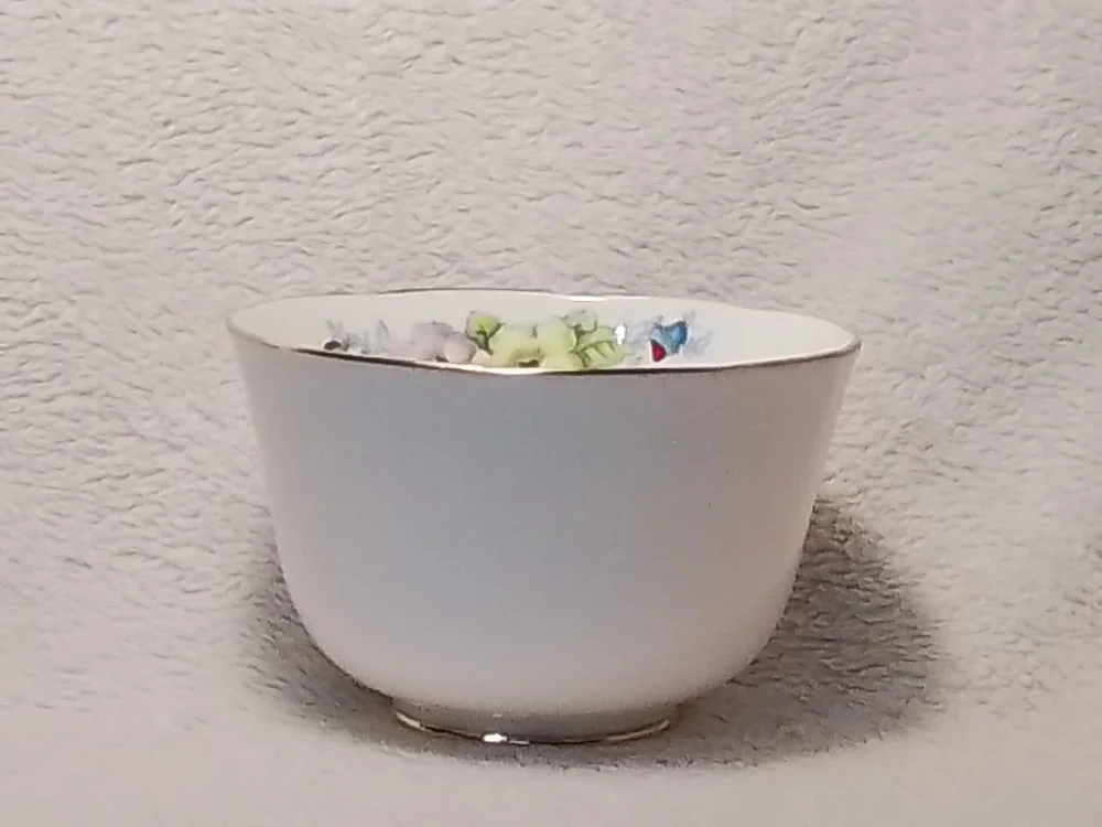 White bowl filled with colorful wrapped candies on a textured white surface.