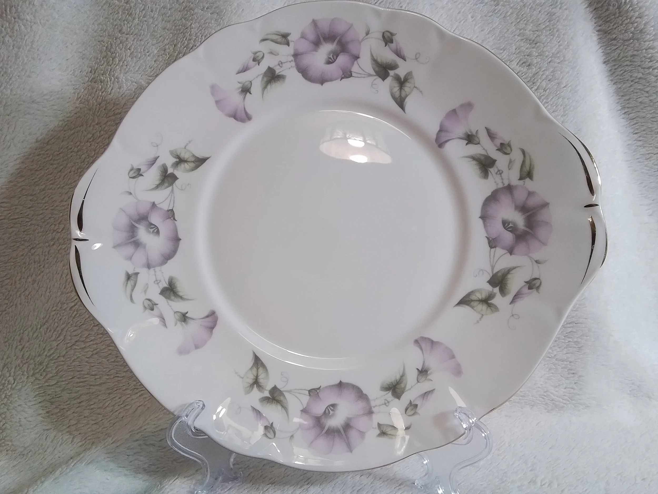 A white ceramic plate with a purple floral pattern around the rim, placed on a soft, light-colored fabric background.