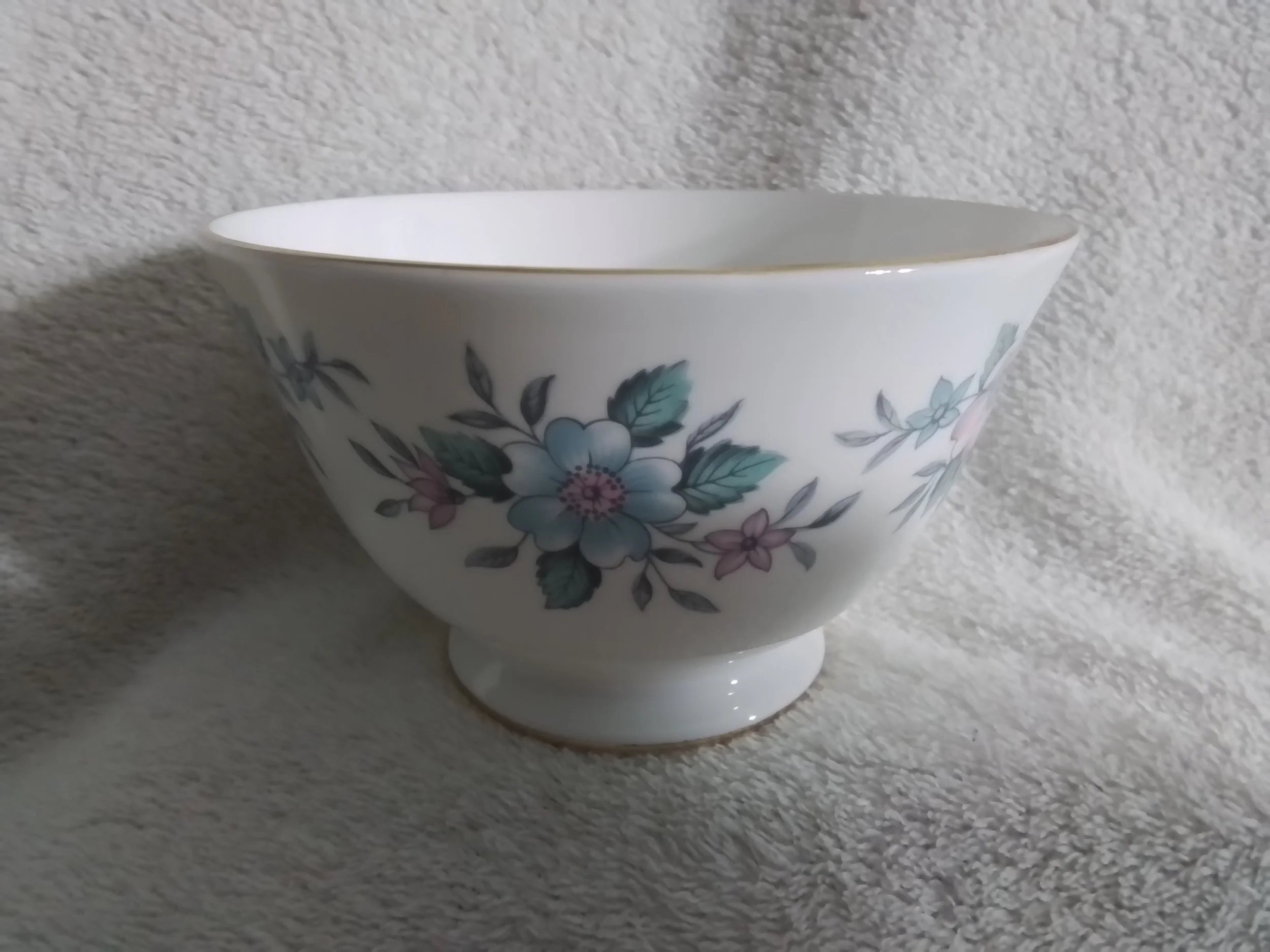 A white ceramic bowl with a floral pattern featuring pink, blue, and purple flowers with green leaves.