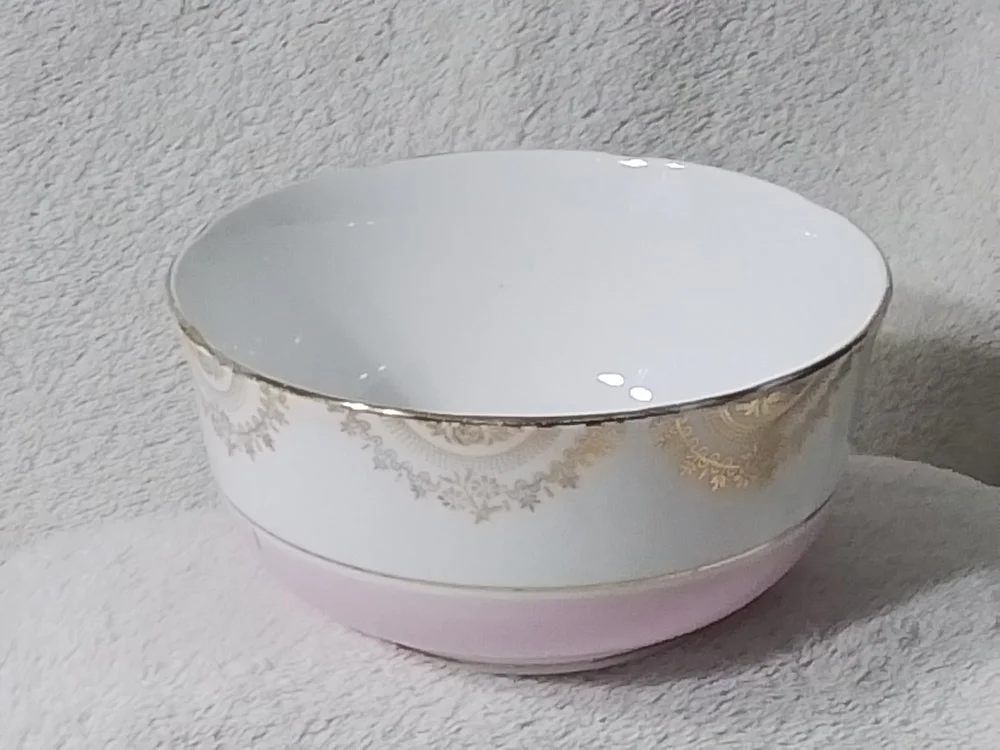 Decorative round ceramic bowl with gold accents on a textured surface.