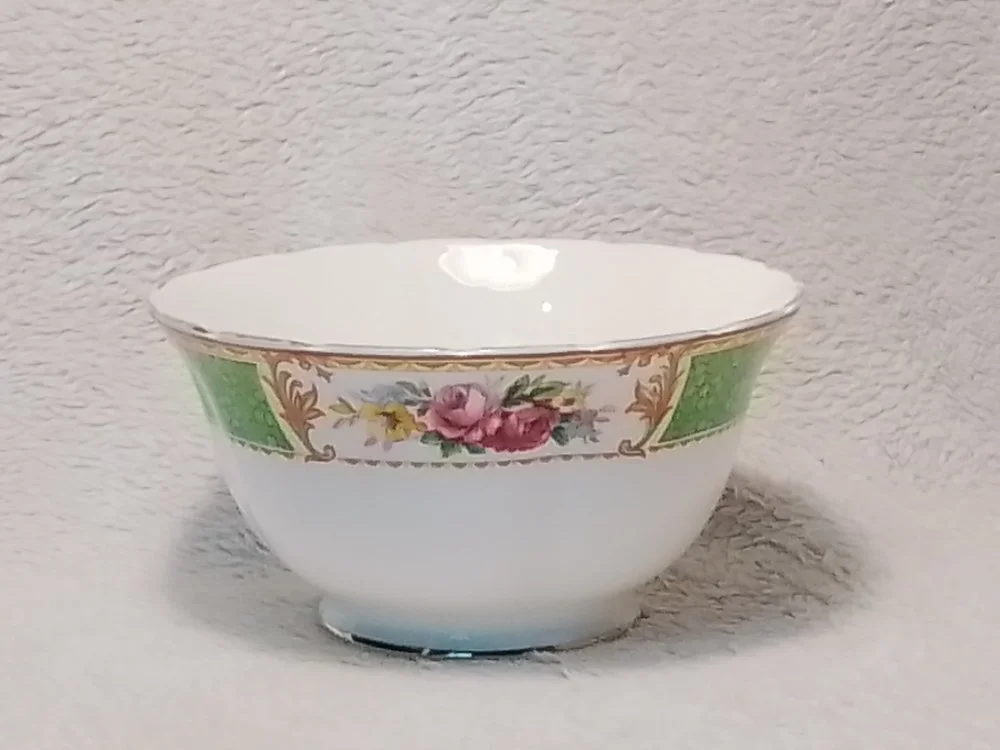 A white ceramic bowl with pink, yellow, and purple floral design and gold trim along the rim.