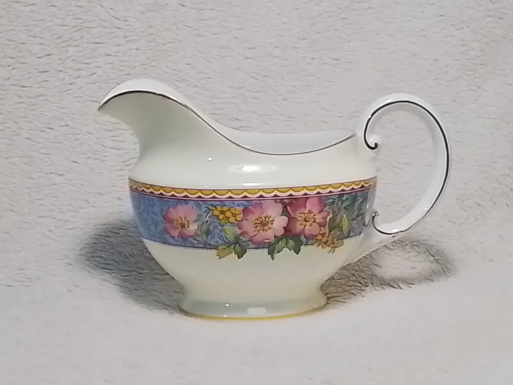 Decorative porcelain gravy boat with a floral design and gold accents.