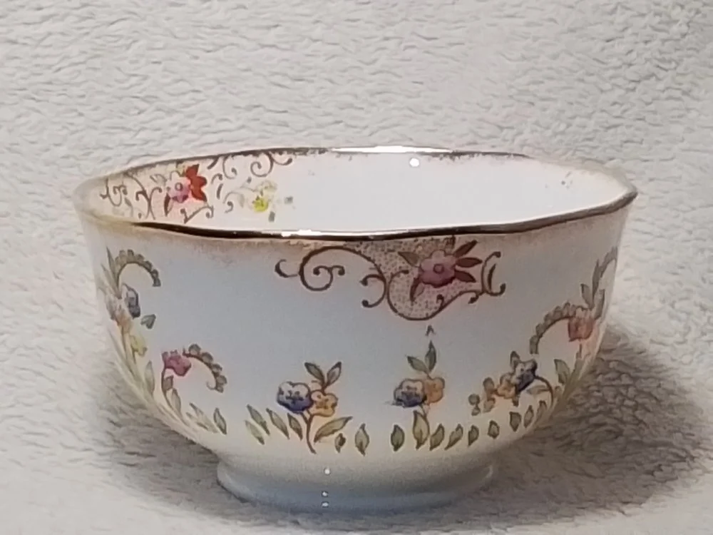 Decorative porcelain bowl with floral patterns and a dragon design seen against a textured white background.