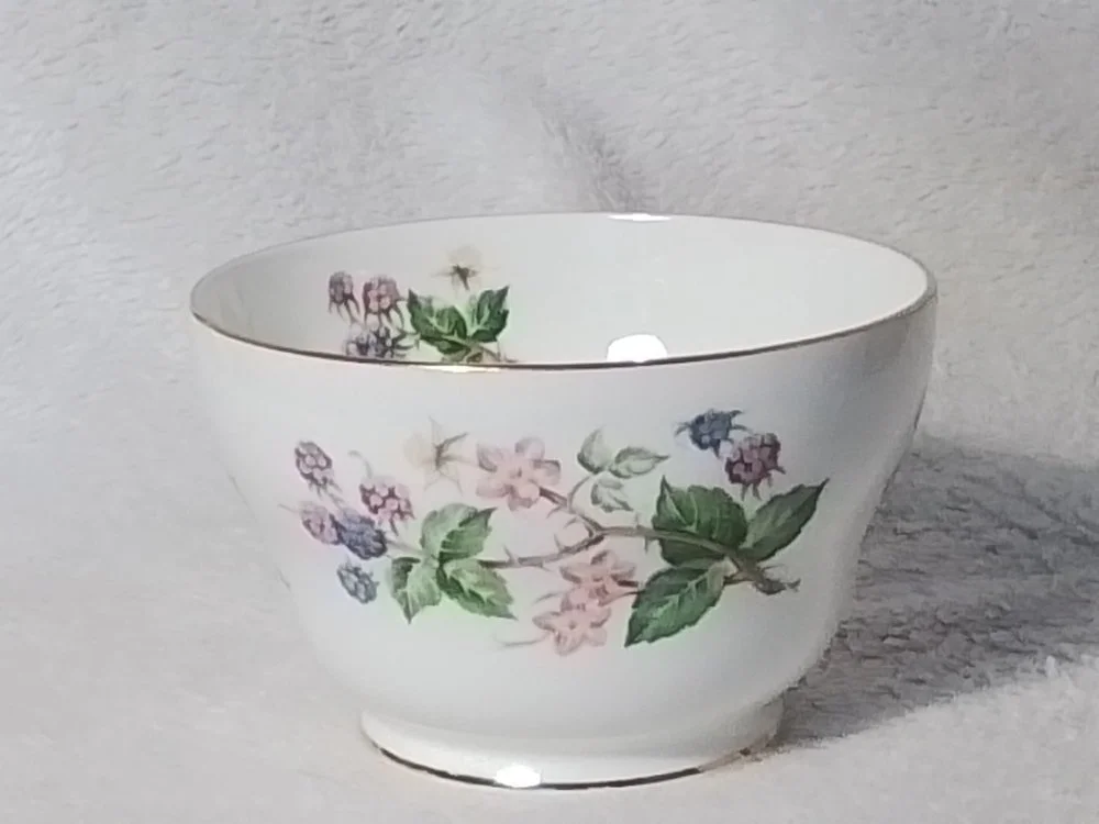 A white porcelain bowl with a floral pattern of pink and purple flowers with green leaves