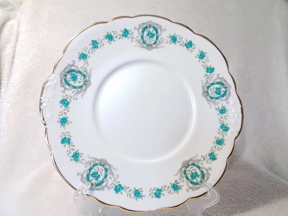 A decorative porcelain plate with a gold scalloped edge and blue floral and ornate patterns on a white background.