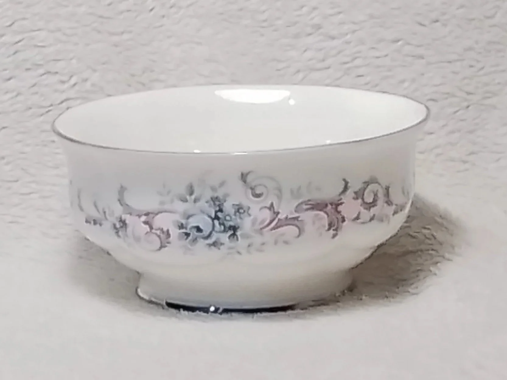 A white ceramic bowl with decorative floral patterns on a plain background.