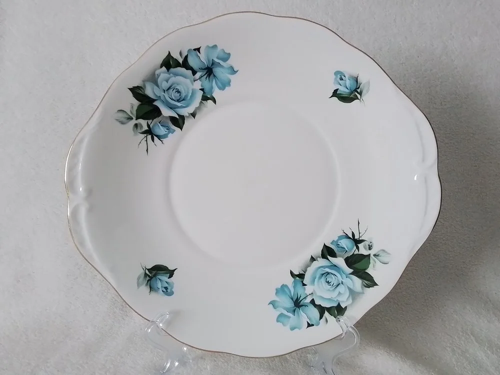 White porcelain plate with a scalloped edge and blue floral pattern, featuring roses and leaves along the rim.