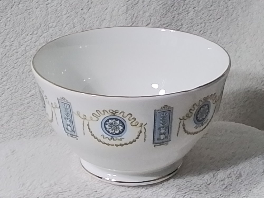 White bowl with blue and gold decorative pattern on a white surface.