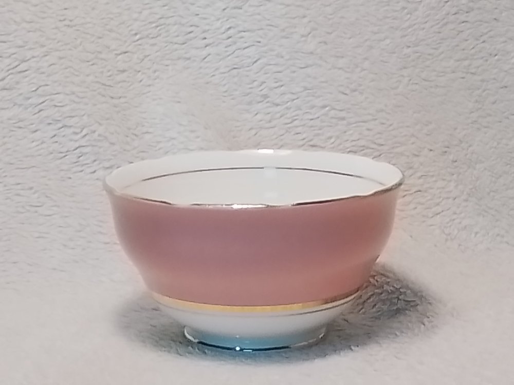 A pink and white porcelain bowl placed on a textured off-white surface with a textured off-white background.