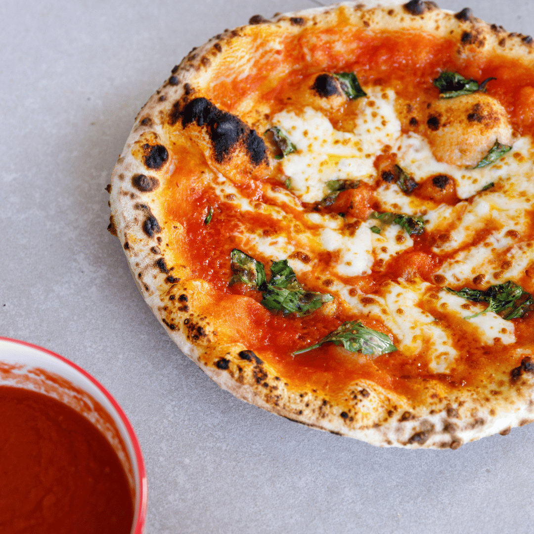 Neapolitan style Margherita pizza made with quality tomatoes, mozzarella and fresh basil.