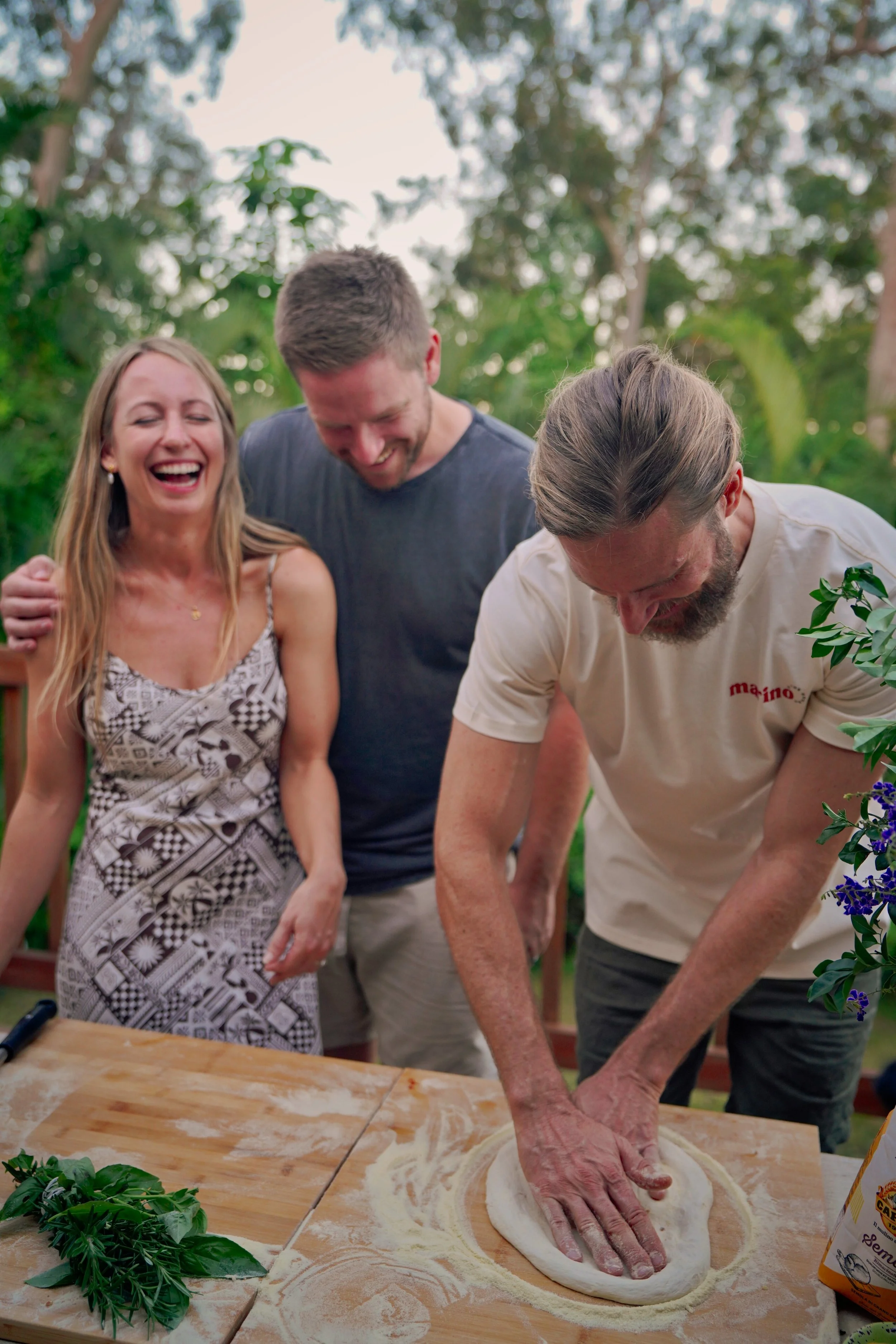 Dough Artisan Luke Marino shaping pizza dough outdoors while guests smile and watch during a private masterclass.