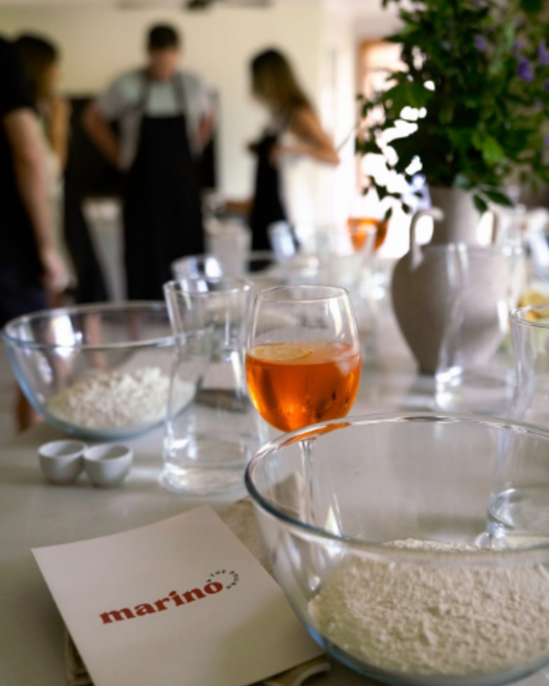 Fresh pizza being shared at the table with burrata, herbs, and drinks in a relaxed social setting