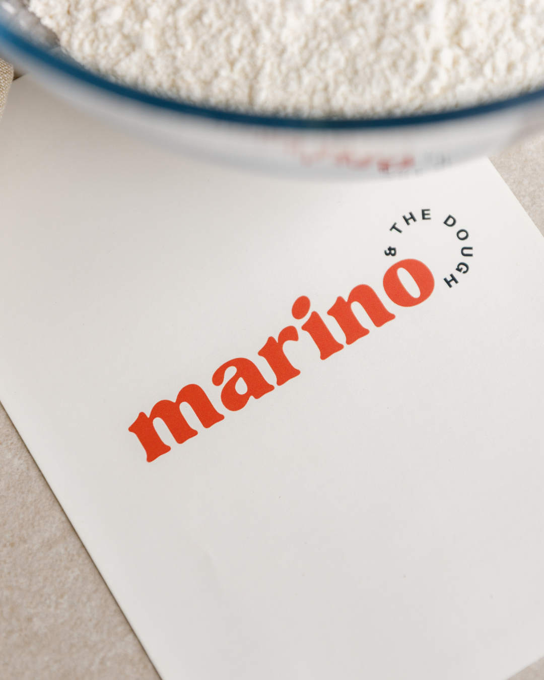 Marino & The Dough recipe notebook beside a bowl of flour, ready for a hands on pizza making masterclass.