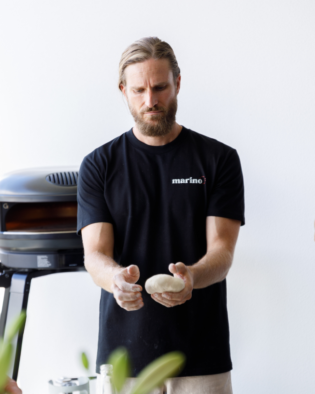 Luke Marino demonstrating how to shape a pizza dough ball during a hands on pizza making masterclass with guests.