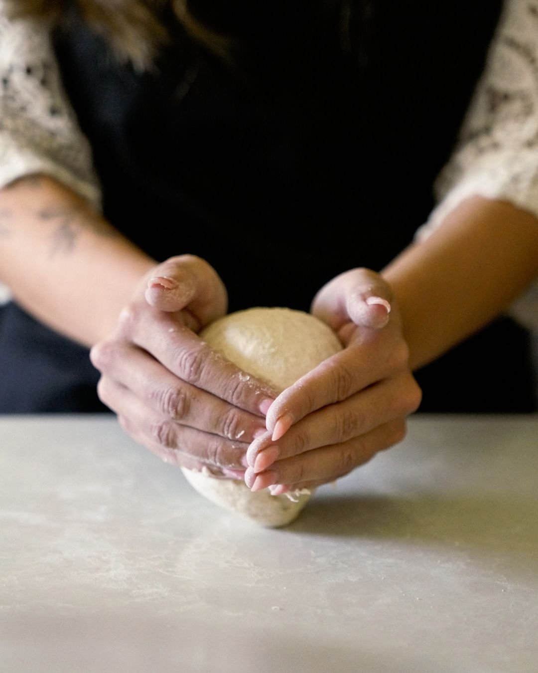 A close-up of hands gently shaping a ball of pizza dough during a Marino & The Dough masterclass, highlighting the tactile care and precision behind every great crust.