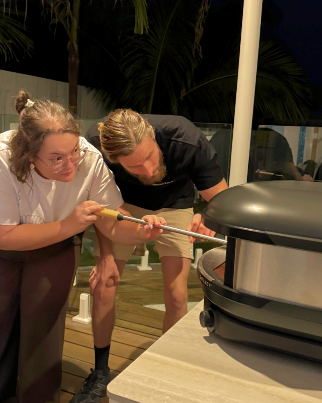 Hen’s party guest learning to turn a pizza in a Gozney oven with guidance from a pizza instructor during a private masterclass.