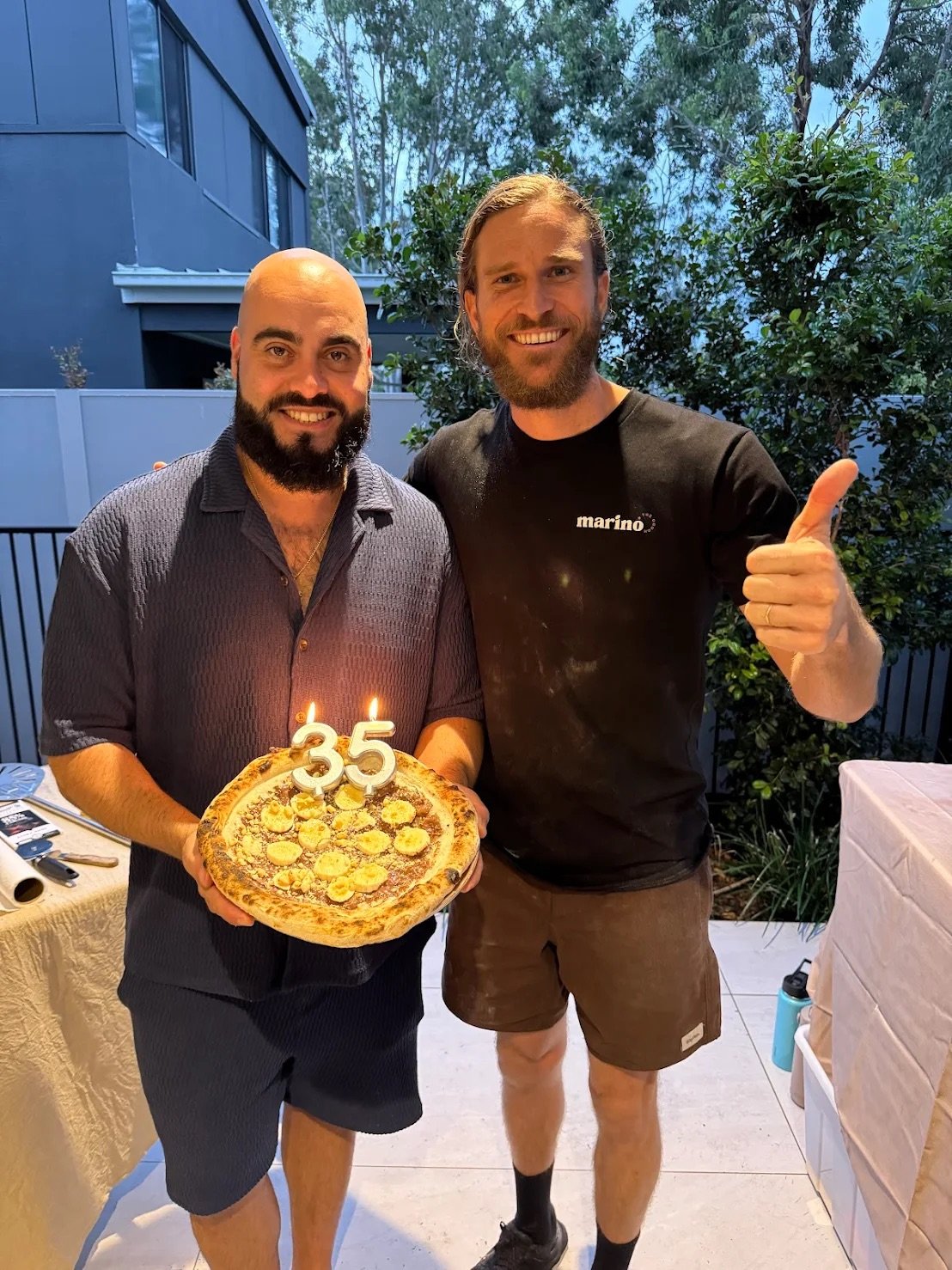 Birthday celebration during a private pizza masterclass on the Gold Coast, with Luke Marino and guest holding a freshly made pizza with candles.