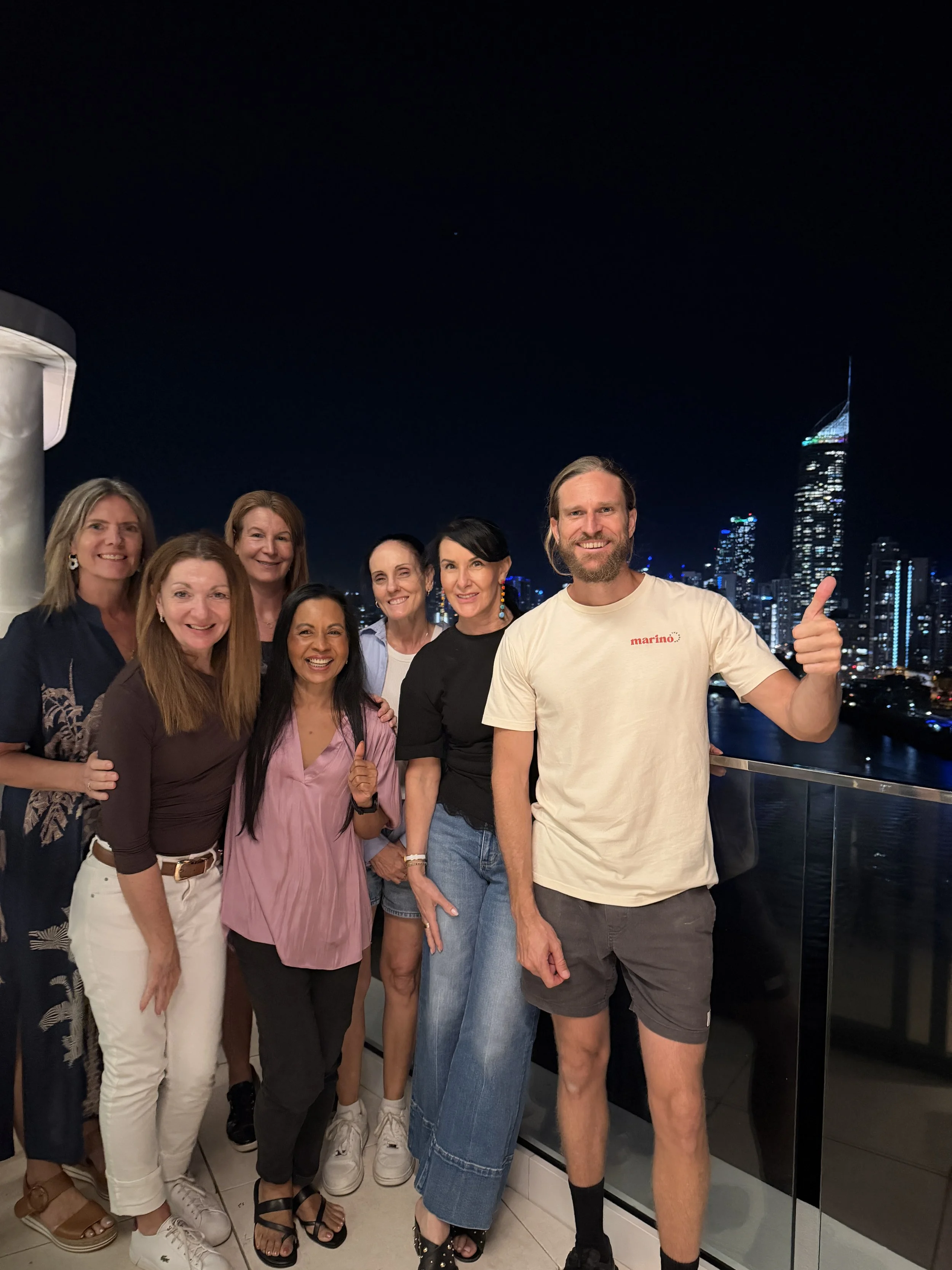 Marino & The Dough host with a group of guests after a private pizza masterclass on a Gold Coast balcony, with the city skyline lit up at night.