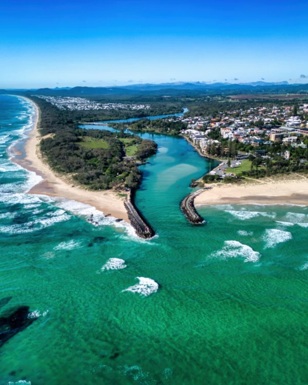 Aerial view of the Northern NSW coastline showing turquoise ocean, sandy beach and river inlet meeting the sea near the Gold Coast.