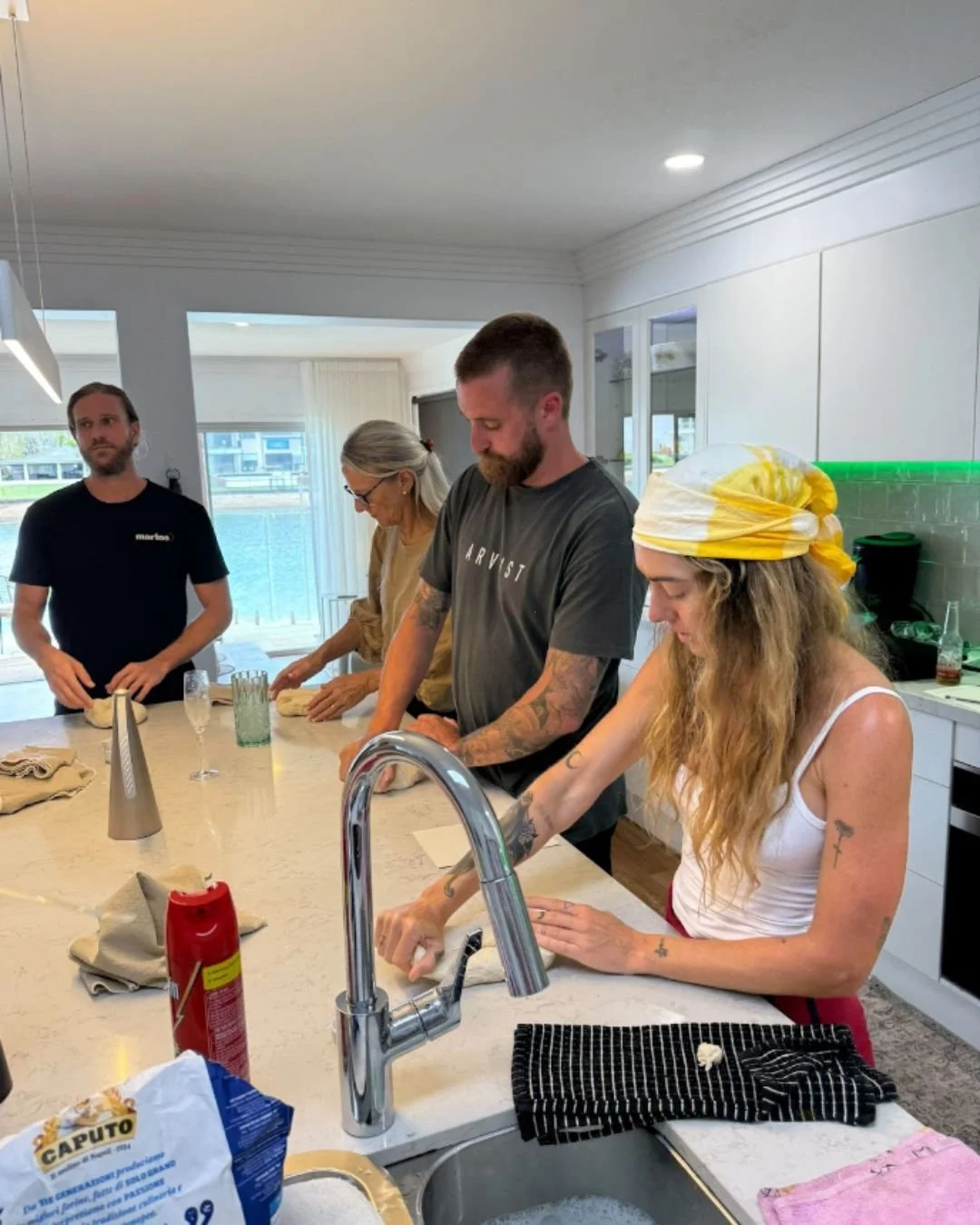 Guests focused on shaping pizza dough during a Marino & The Dough kitchen masterclass, led by dough artisan Luke Marino in a bright, waterfront home setting.