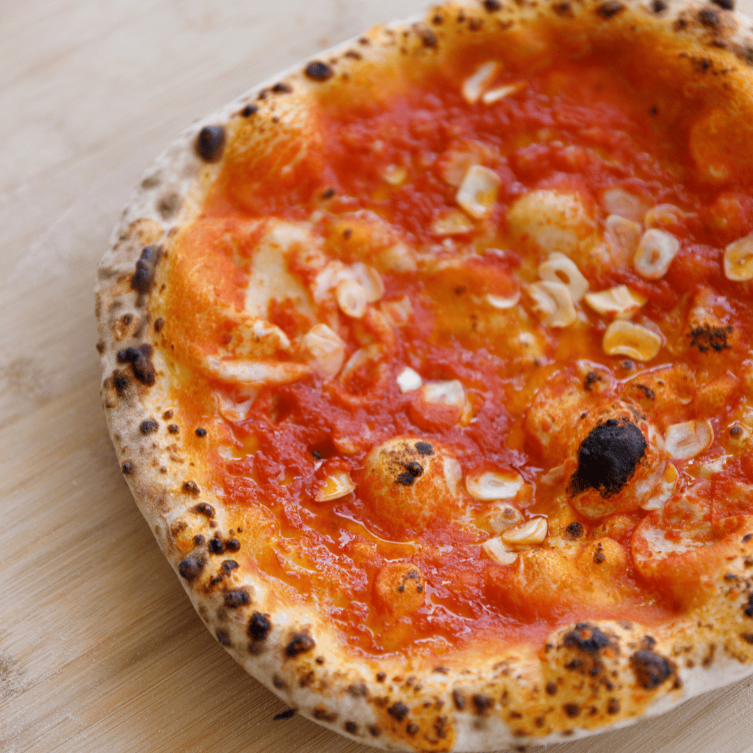 Close up of Neapolitan pizza crust showing blistering and colour development
