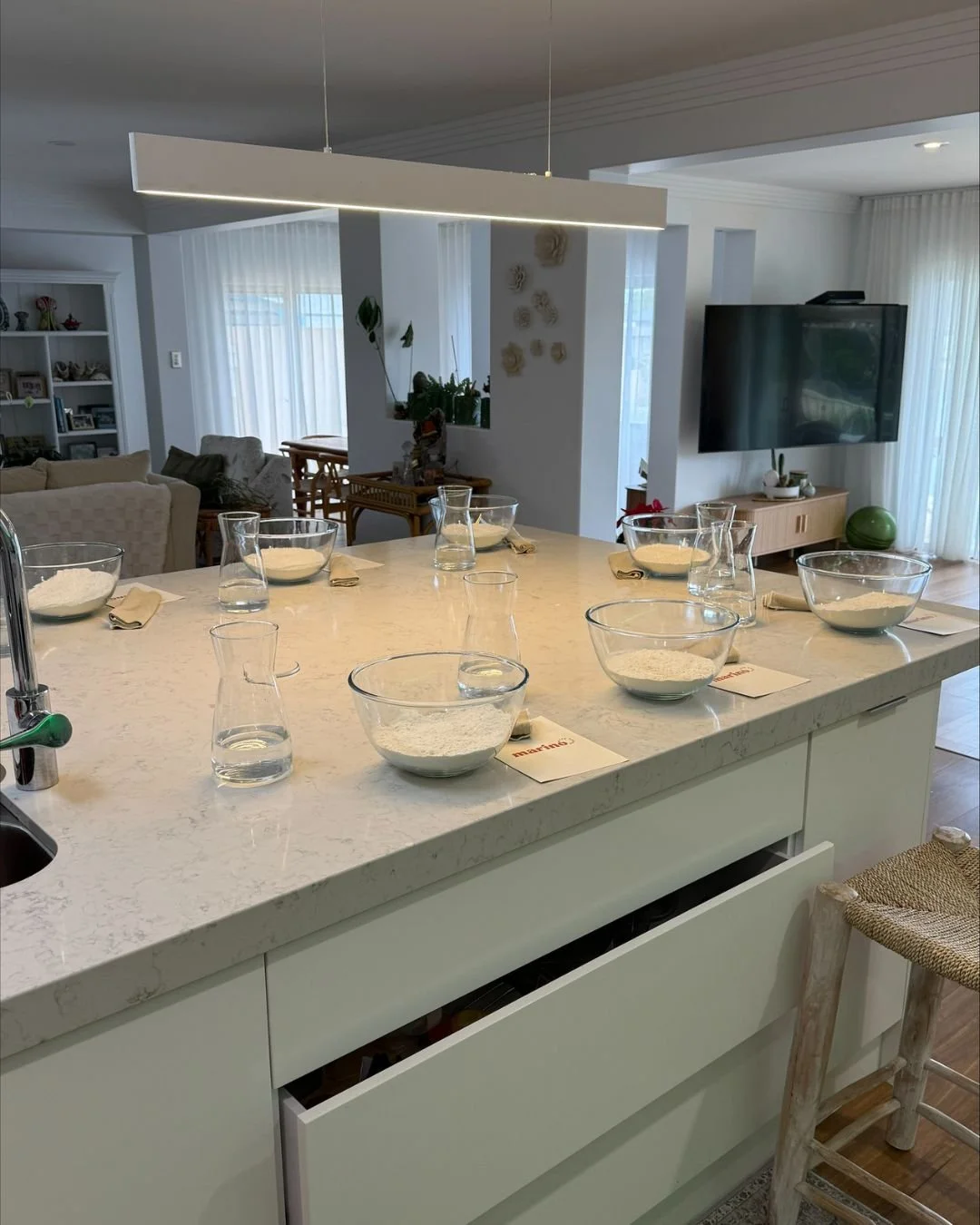 Kitchen island set for a private Marino & The Dough masterclass with glass bowls of flour, water carafes and recipe cards ready for guests