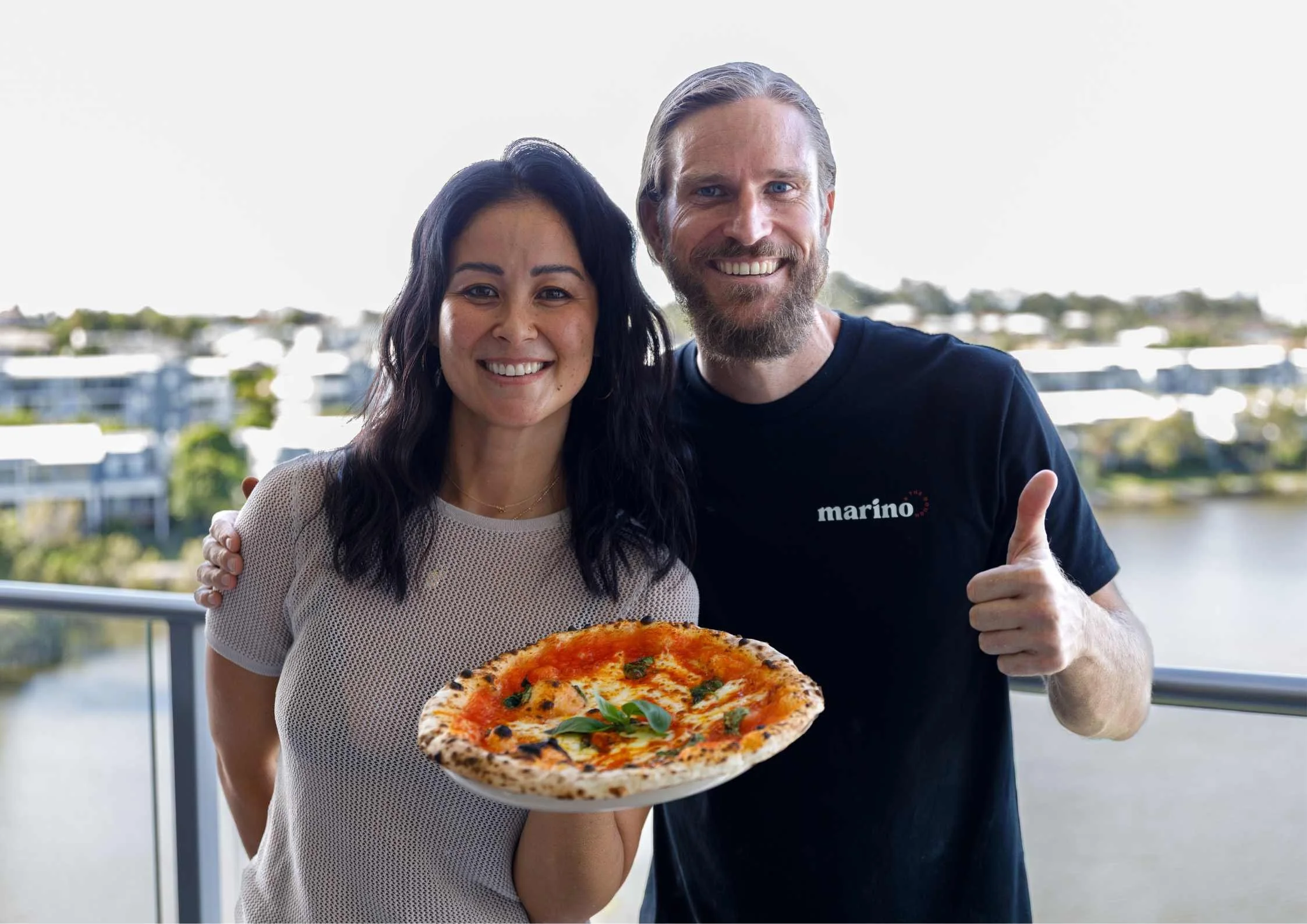 A guest holding a slice of Neapolitan pizza with melted cheese stretching, served fresh from a backyard class in Brisbane
