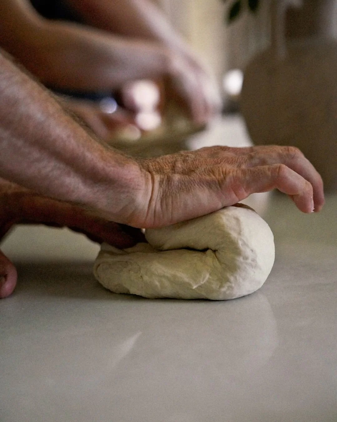 Close-up of a hand kneading fresh pizza dough on a countertop during a Marino & The Dough masterclass, capturing the tactile craft of traditional dough-making.