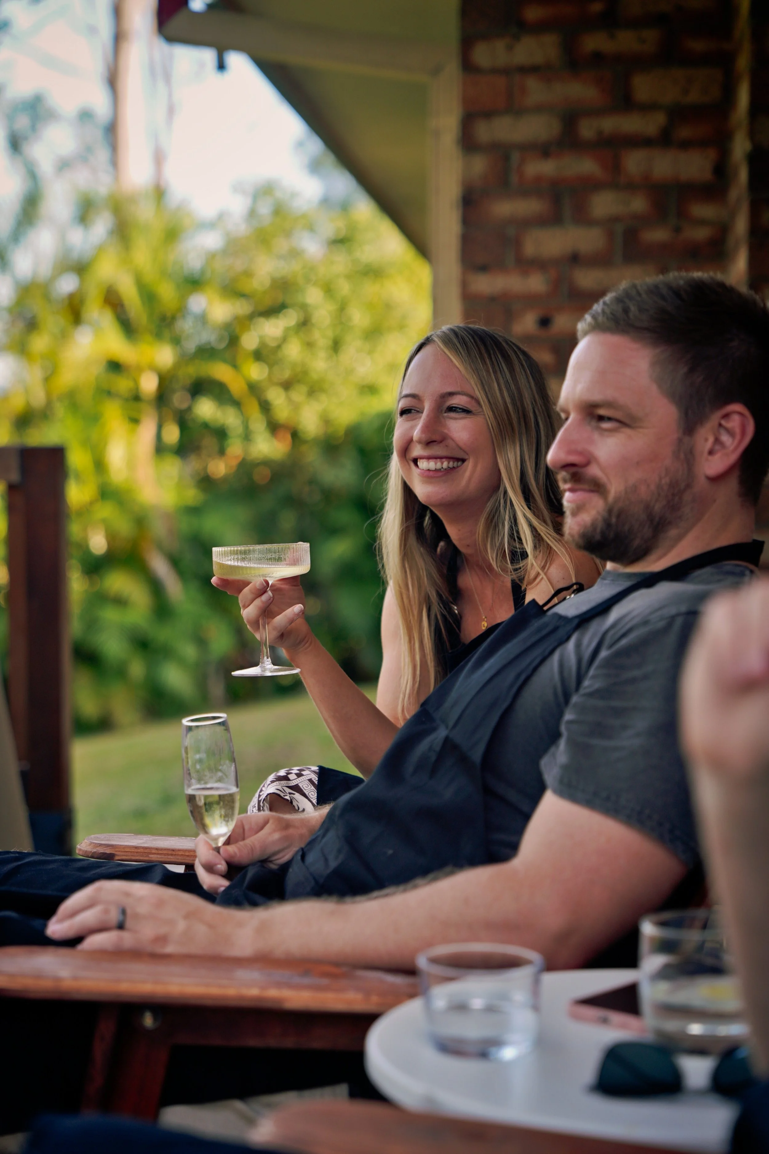 Two guests relaxing with sparkling drinks after a private pizza masterclass in an outdoor garden setting