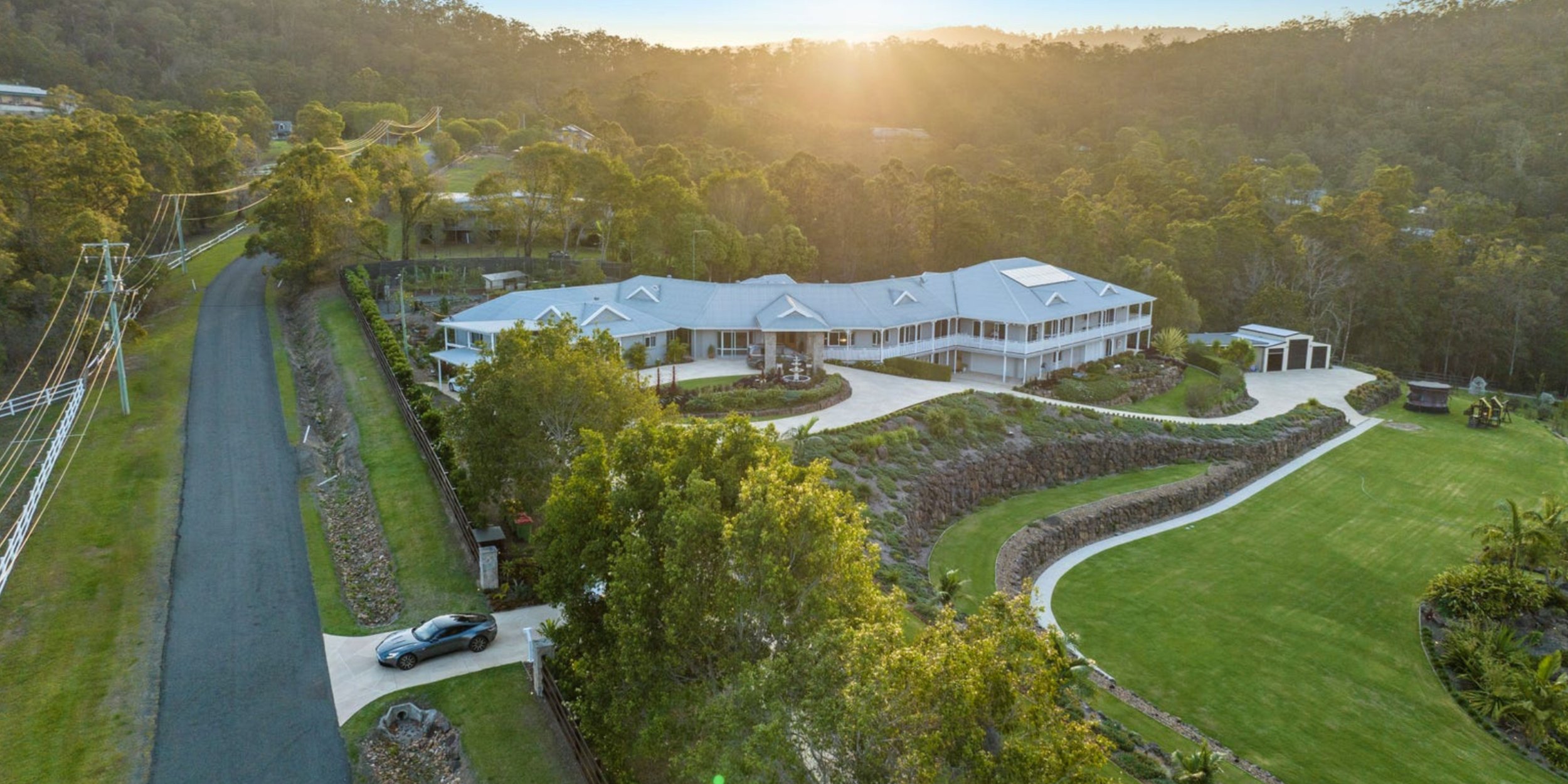 Golden hour aerial view of an expansive Bonogin estate in the Gold Coast Hinterland — elegant wraparound verandah and lush lawns perfect for hosting Marino & The Dough’s private outdoor masterclasses.