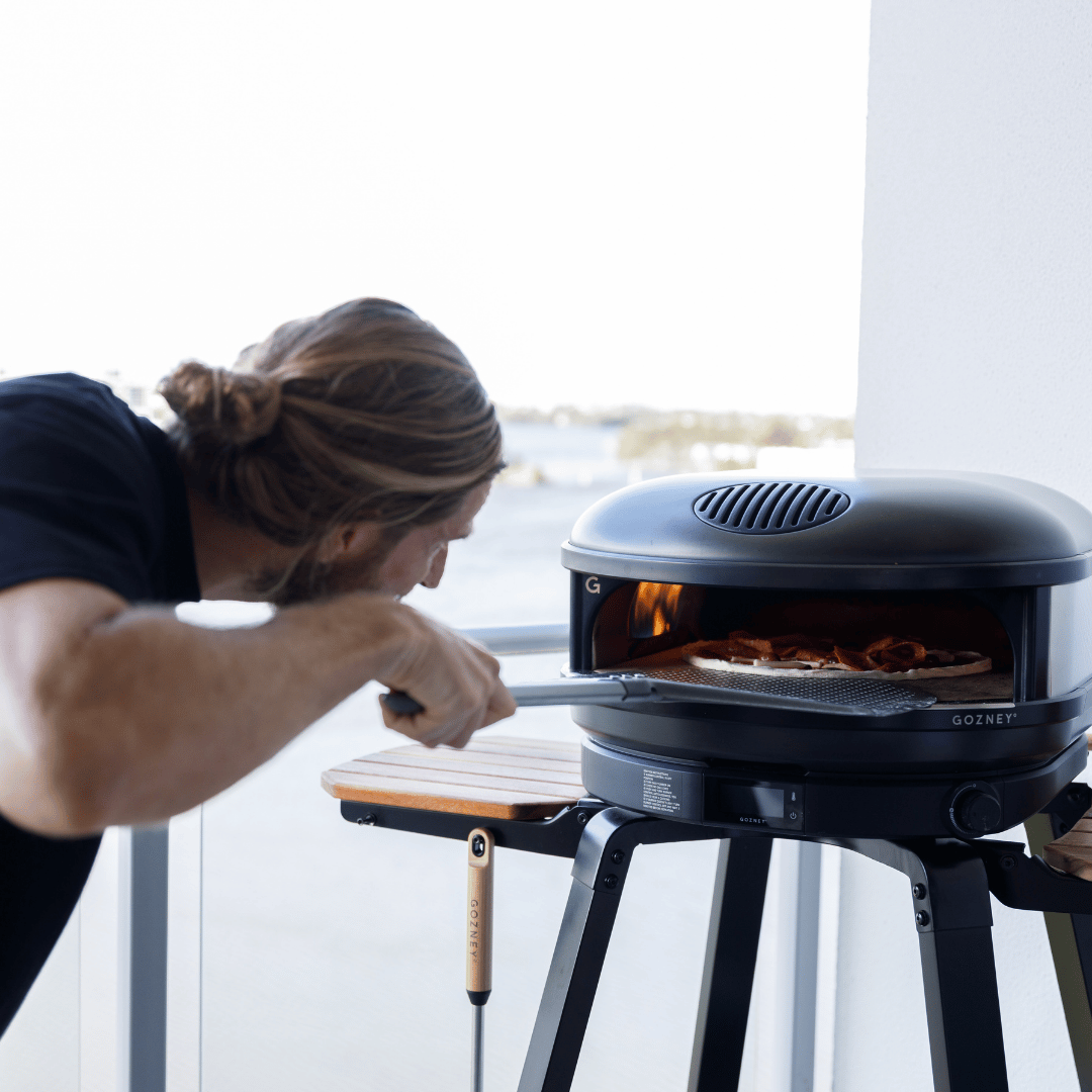 Luke Marino monitoring pizza crust development and heat balance inside a Gozney pizza oven during a private pizza masterclass.