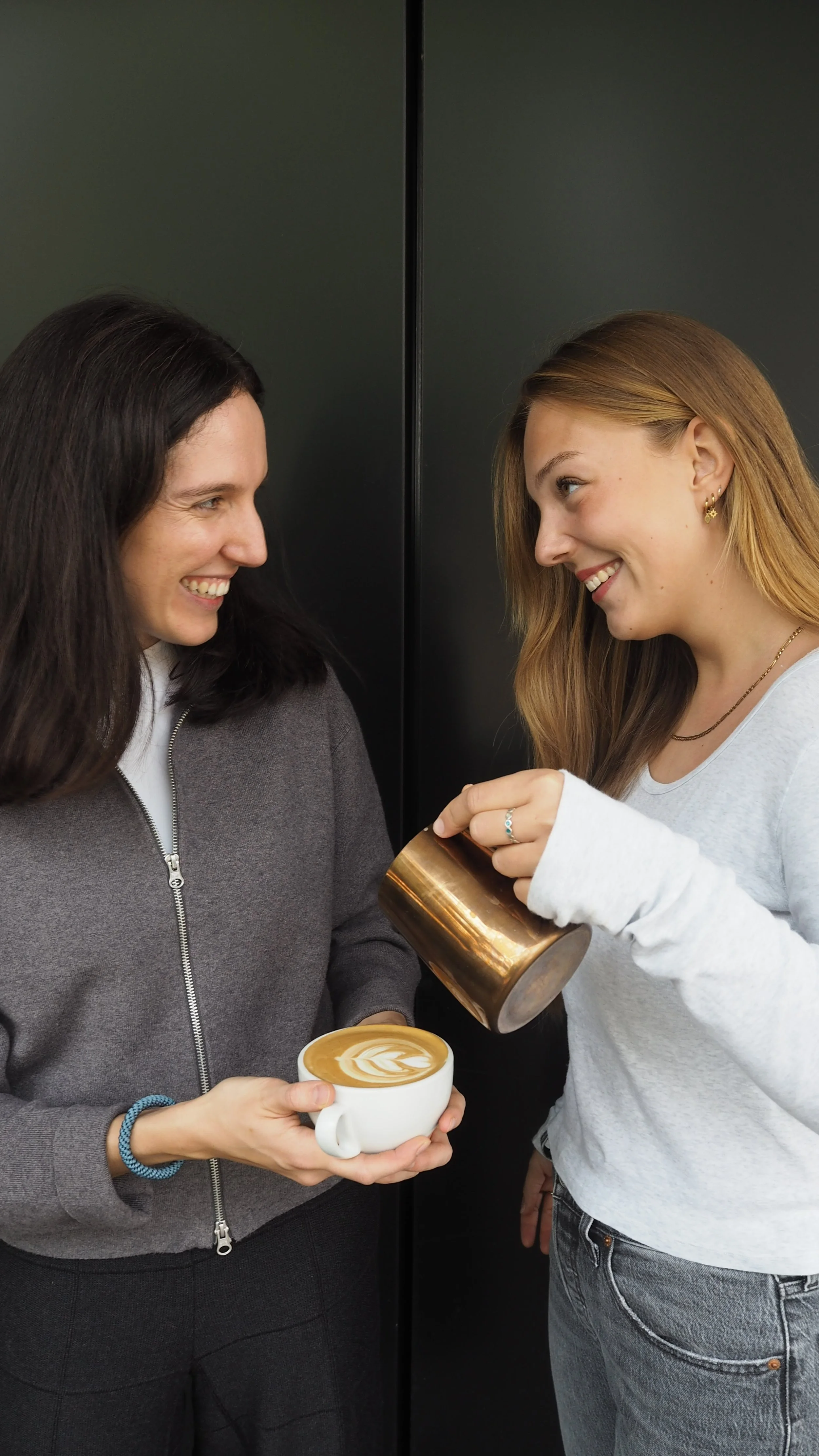 2 Mitarbeiterinnen haben Spaß beim Latte Art üben