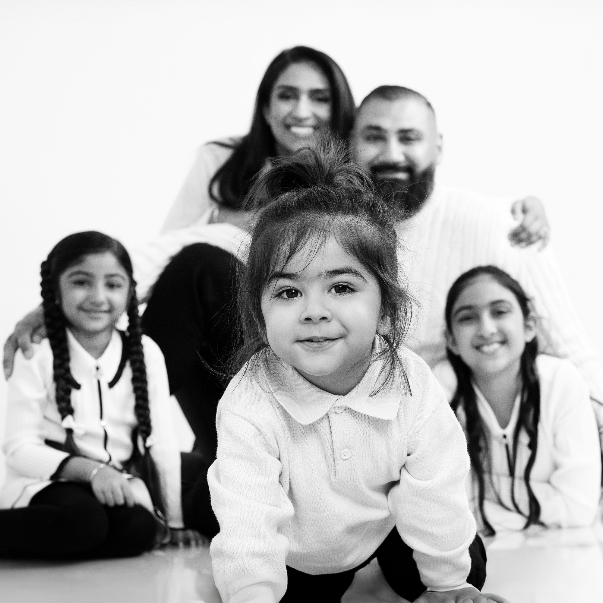 A family of five, including children and adults, gathered together, smiling, in a black and white photo.